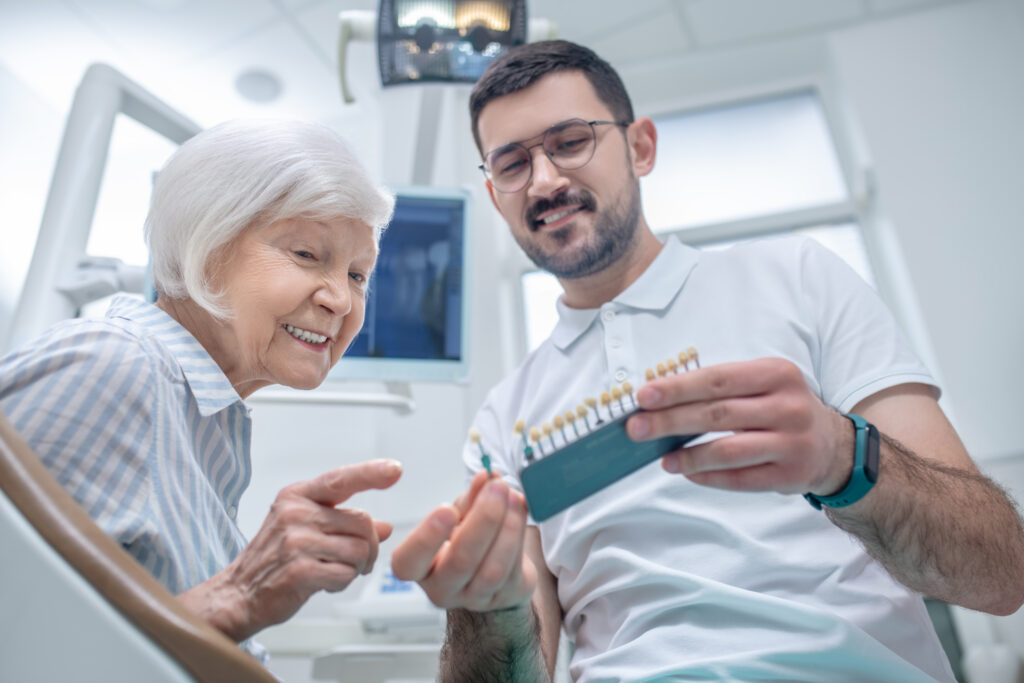 Dental implants. Male young dentist choosing dental implant with his patient